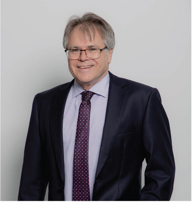 Chris Kohler, Croy Legal associate, dressed in a dark suit with a light striped tie, smiling with a light background